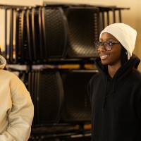 3 students smile while listening to speaker